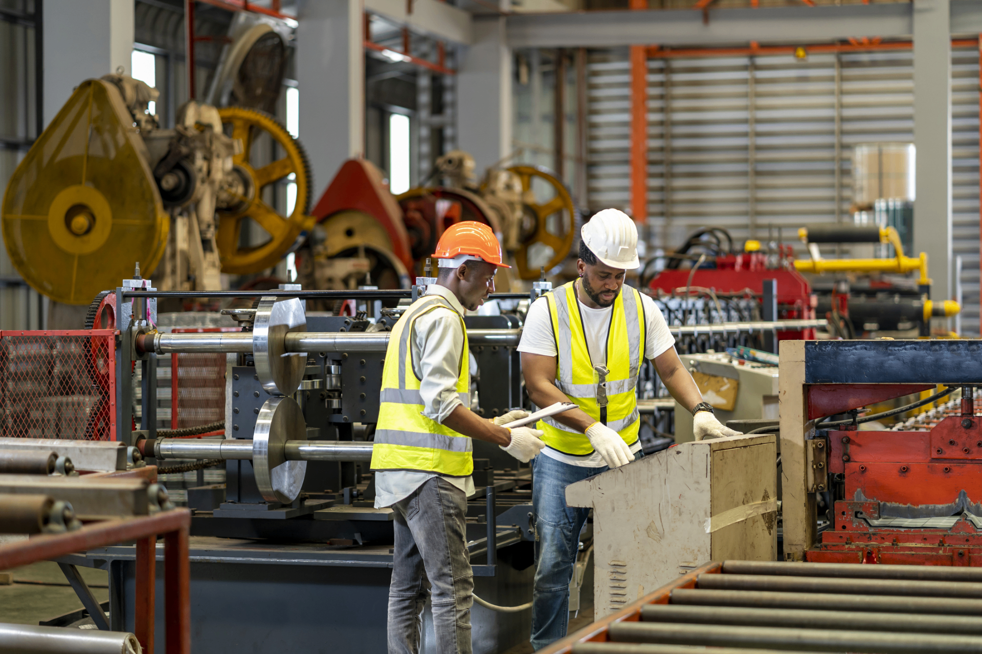Workers collaborating on busy manufacturing floor with heavy machinery