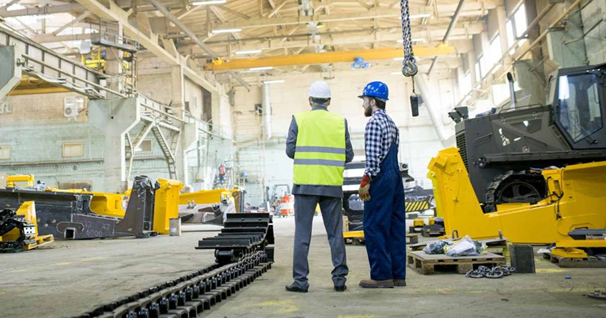 Workers inspecting heavy equipment in manufacturing facility